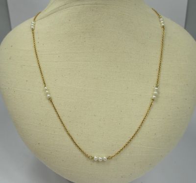 a gold necklace with pearls on a mannequin neck