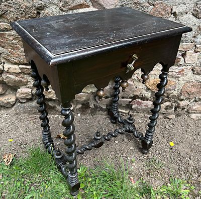 une petite table avec un tiroir, placée devant un mur en pierre
