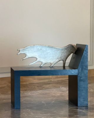 a bench with a metal sculpture on it in a room