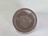 a brown bowl with writing on it sitting on a white surface