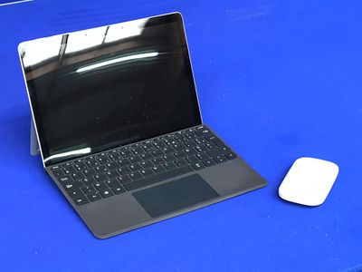 un ordinateur portable posé sur une table bleue, à côté d'une souris