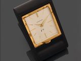 une image représentant une horloge noire et dorée posée sur une surface noire