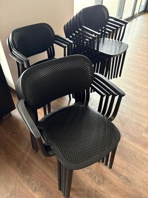 Plusieurs chaises en plastique noir sont alignées dans une pièce