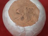 une boule blanche ornée d'un motif marron sur un fond rouge