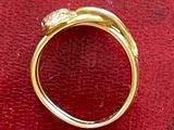 une image montrant un gros plan d'une bague en or posée sur une surface rouge