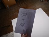 a person holding up a piece of paper with numbers on it