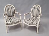 une paire de chaises peintes en blanc, avec des coussins rembourrés à rayures