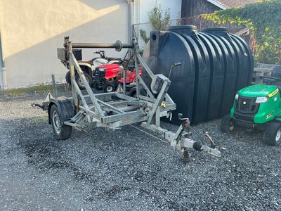 une remorque attelée à un tracteur, à côté d'un réservoir
