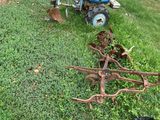 a blue tractor and a plow in the grass