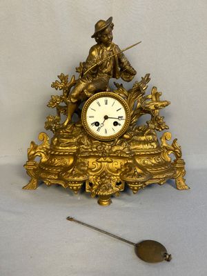 une horloge en or posée sur une table, à côté d'une cuillère