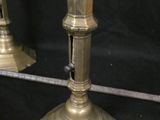 two brass candlesticks and a baseball bat on a black background