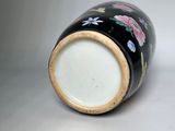 a black and white vase with flowers painted on it