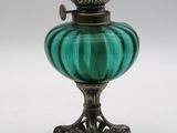 une lampe à huile en verre vert posée sur un support muni d'un socle en métal