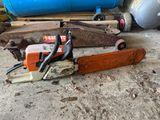 a picture of a chainsaw sitting on the ground next to a blue barrel
