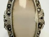 an oval ring with a white stone surrounded by black diamonds