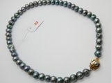 un gros plan d'un collier muni d'un fermoir doré, posé sur une surface blanche