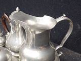 a silver plate with a silver pitcher and two silver cups on it