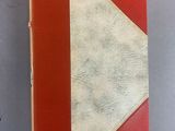 an orange and white book with a red cover on a gray surface