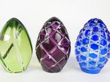 three different colored glass vases sitting next to each other on a white surface