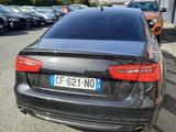the rear end of a black car parked in a parking lot