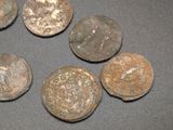 six ancient roman coins on a table with a black background