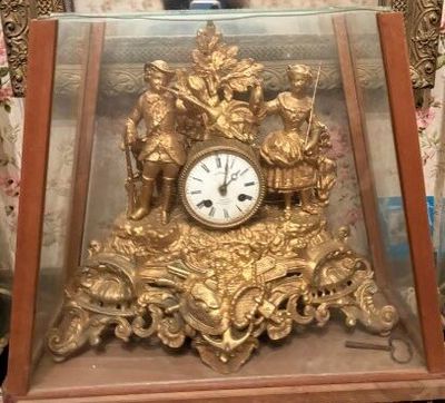 une horloge en or posée dans une vitrine, sur une table