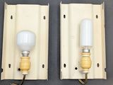 two light bulbs on a wall mounted light fixture on a gray surface