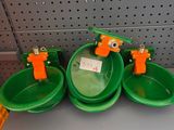 three green bowls with orange handles on a shelf