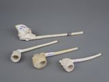 four bone pieces and a pipe holder on a gray surface