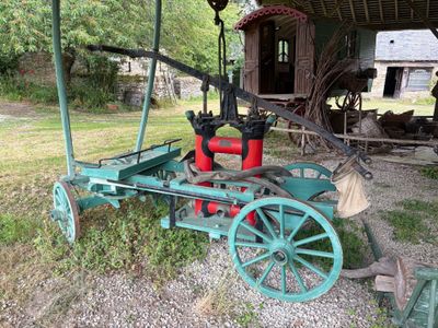un petit tracteur vert avec un réservoir rouge à l'arrière
