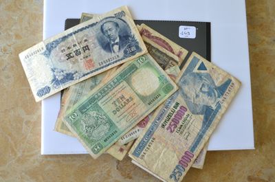 de nombreux billets de banque de différentes valeurs posés sur la table, à côté d'un ordinateur portable