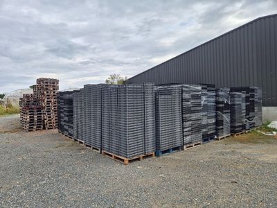 de nombreuses piles de briques empilées sur une palette devant un bâtiment