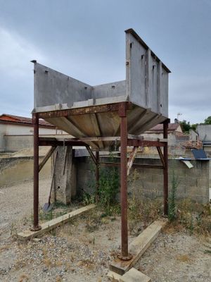 une structure en béton érigée au milieu d'un terrain en terre battue