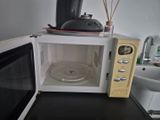 a microwave with a tea pot on top of it