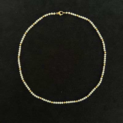 un collier de perles avec un fermoir en or sur fond noir