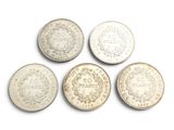 six types différents de pièces d'argent sur une surface blanche