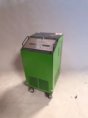 a green machine sitting on top of a white floor next to a wall
