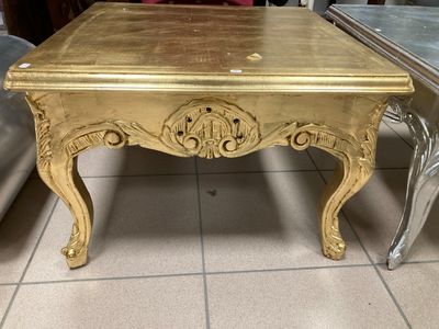 a gold table that is sitting on a tile floor