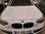 une BMW blanche garée dans un garage, avec d'autres voitures en arrière-plan