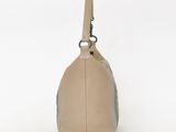 the large beige bag is sitting on a white surface