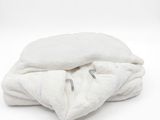 une couverture blanche pliée sur une surface blanche