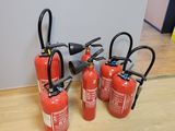 Quatre extincteurs sont alignés sur un plancher en bois