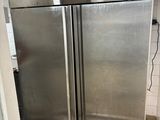 two stainless steel refrigerators in a kitchen with tile flooring
