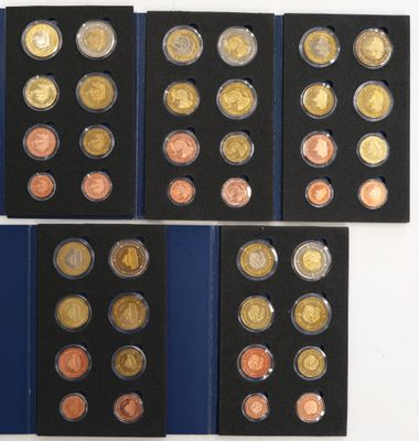 a group of six different coins in a display case