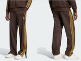 a man in a brown track suit standing next to another man in white shoes