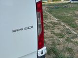a white van parked in a field with a barn in the background