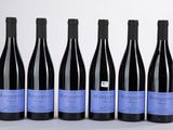 six bouteilles de vin sont alignées sur une surface blanche