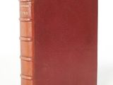 an old book with a brown cover sitting on top of a white surface