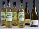 Plusieurs bouteilles de vin blanc sont alignées sur une table