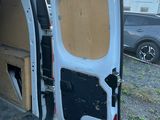 une camionnette blanche dont la porte est ouverte, garée sur le bord de la route